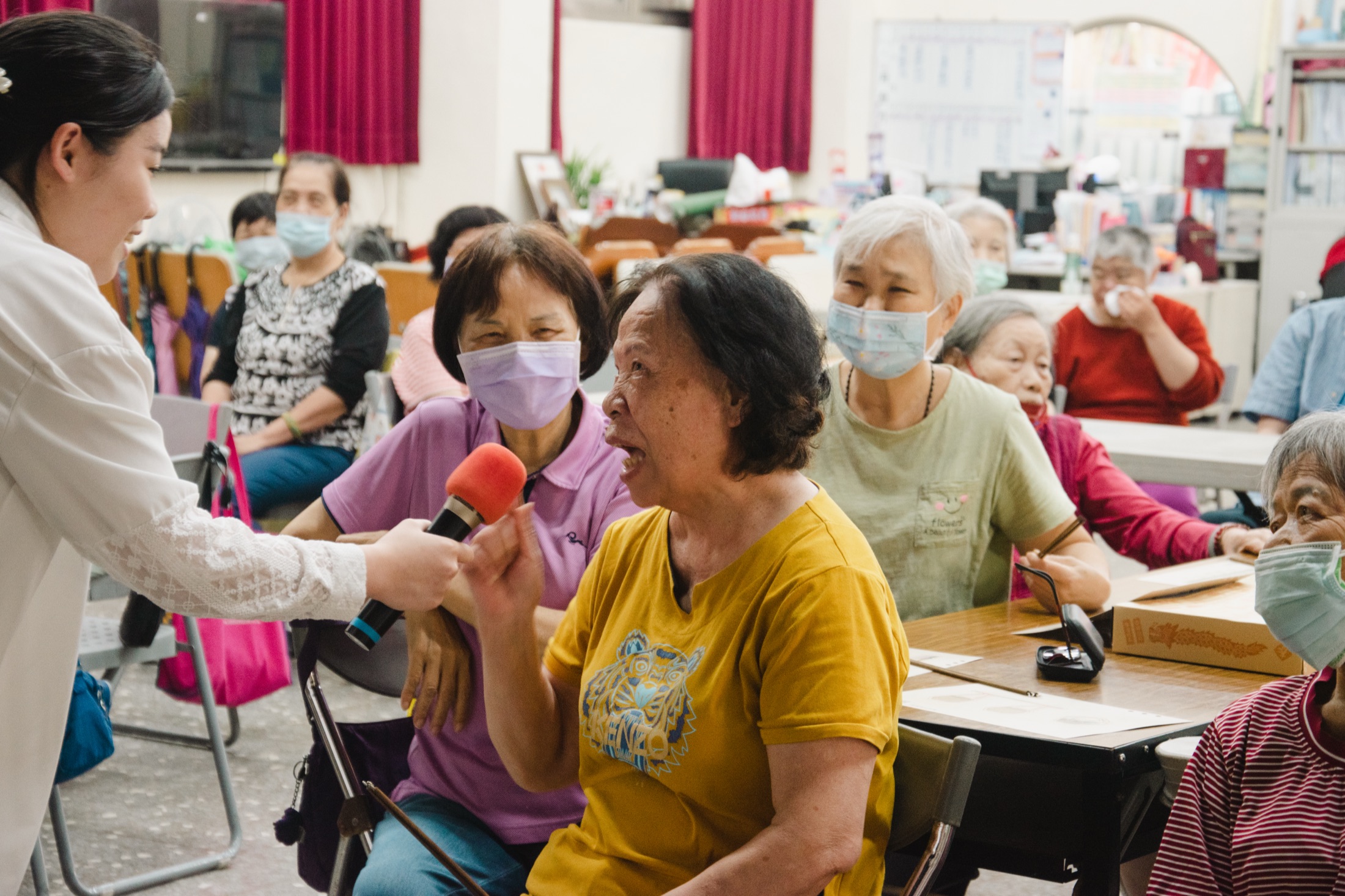 Field observation — researcher interviewing elderly participant with microphone