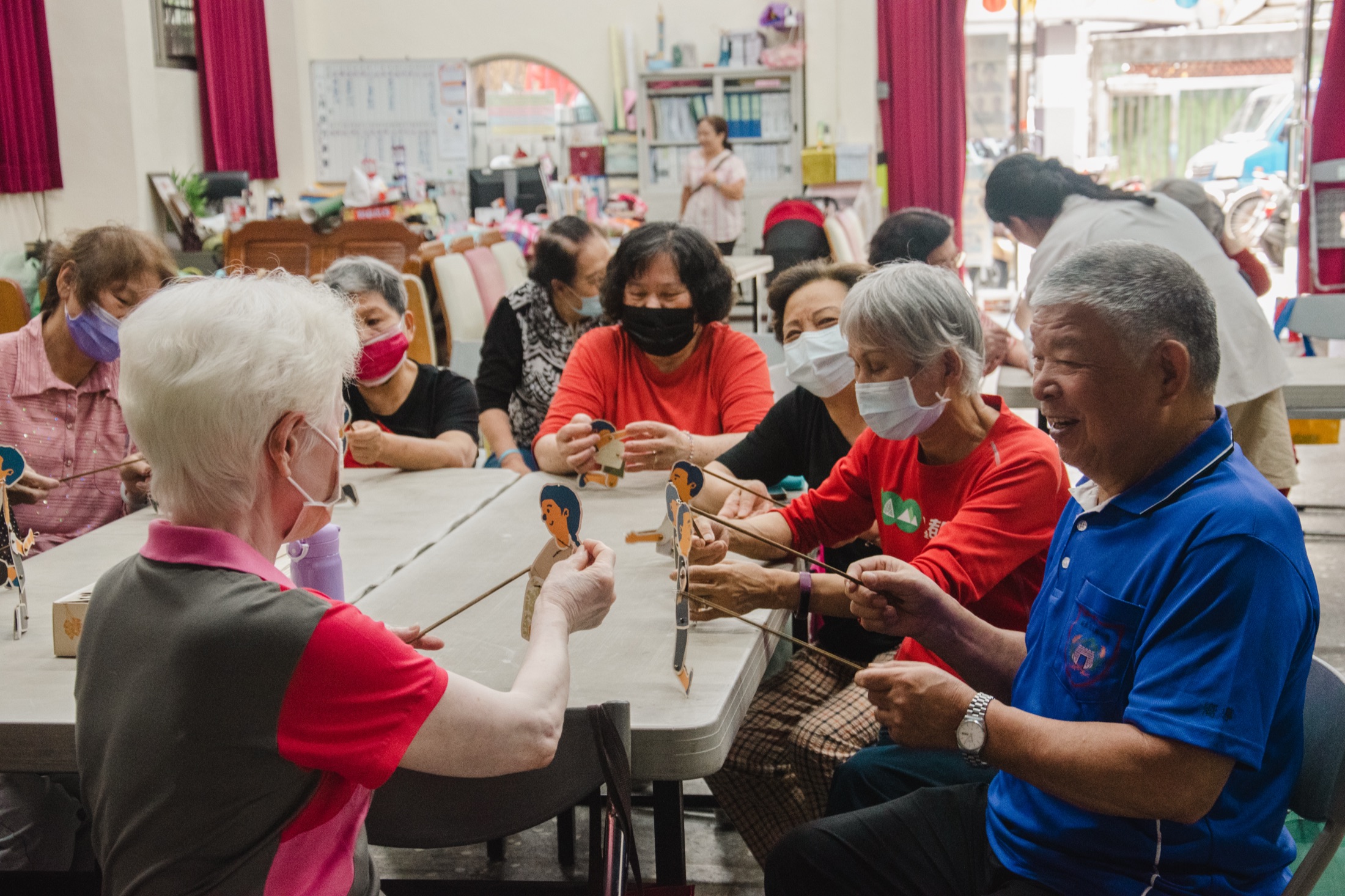 Co-design workshop — elderly participants assembled around table with puppet figures